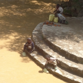 Enfants en train de puiser dans la rivière aux eaux sales de la SEBEYA.