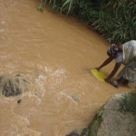 Une femme et son bébé au dos dans la rivière SEBEYA à la recherche d’eau